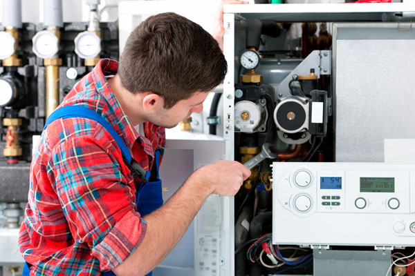 Heating technician repairing boiler controls in Davis