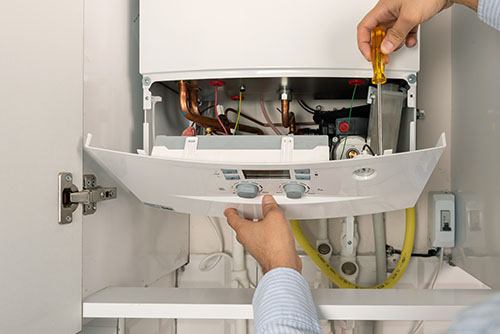 Heating technician repairing a residential boiler in Davis