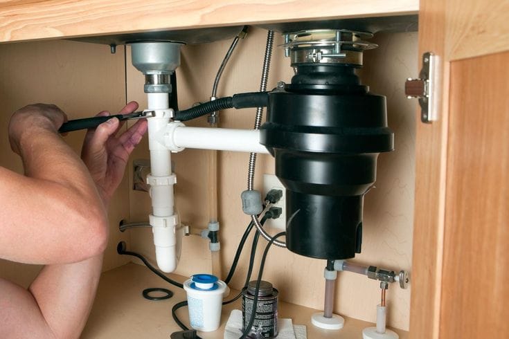 Plumber repairing a garbage disposal in Davis