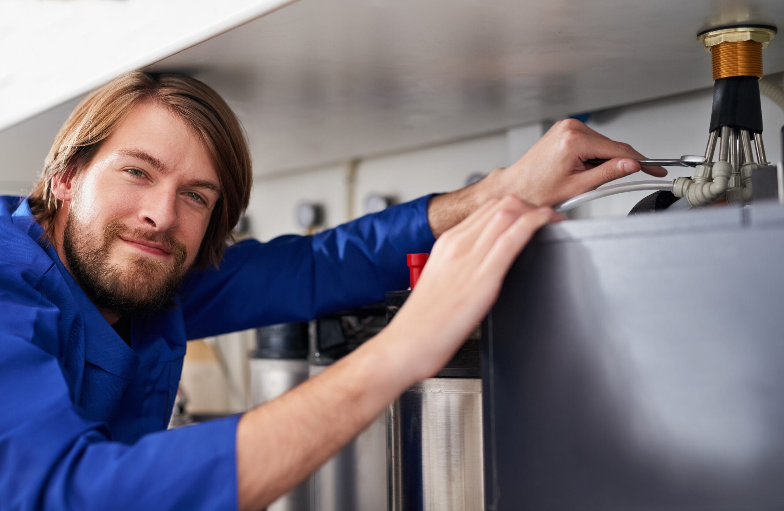 Technician servicing a residential water heater tank in Davis